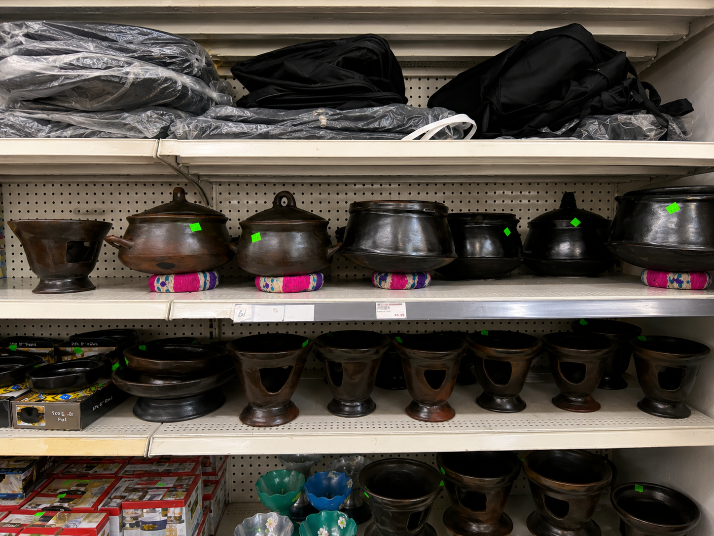 Organized display of black pottery with colorful decorative fabric handles